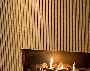 Stijlvolle open haard in Vakantiehuisje in Ballum, Ameland biedt warmte en sfeer voor een knusse vakantie.