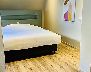Slaapkamer met houten vloer in Vakantiehuisje in Ballum, Ameland, biedt comfort en stijl op de Waddeneilanden.