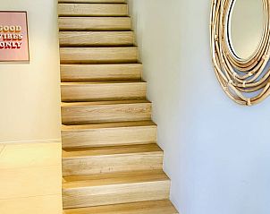 Houten trap in Vakantiehuisje in Ballum, Ameland leidt naar gezellige bovenverdieping, perfect voor gezinnen.