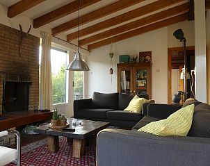 Cozy living room in Jans vacation home, Ballum, Ameland, with fireplace and wooden beams.