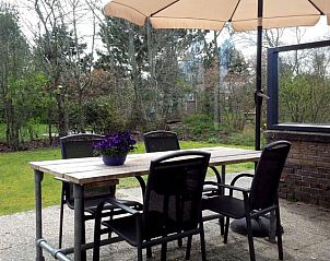 Outdoor area with dining table at Jans vacation home in Ballum, Ameland, surrounded by greenery.