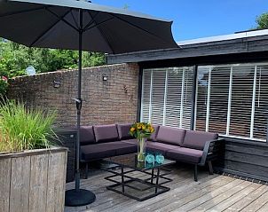 Gemtliche Terrasse am Ferienhaus Artemis in Ballum, Ameland, mit bequemen Loungesofas und Sonnenschirm.
