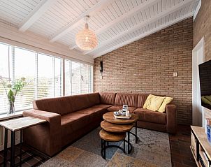 Gemtliches Wohnzimmer des Ferienhauses Artemis in Ballum, Ameland, mit einem Ecksofa und viel Tageslicht.