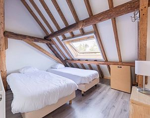 Sfeervolle slaapkamer met houten balken in Tree Lodge, Ballum, Ameland op de Waddeneilanden.