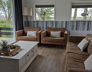 Gezellige zithoek in Lodge 't Pandje, Ballum, Ameland met uitzicht op de natuur door grote ramen.