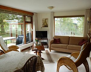 Cozy living room in Thuishaven vacation home, Ballum, Ameland, with large windows.