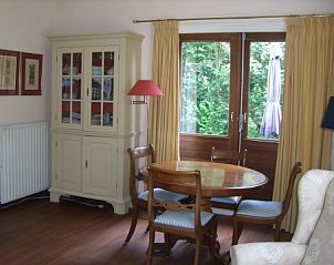 Essecke im Akkerduin Ferienhaus Ballum, Ameland mit Holztisch und Blick auf den Garten der Watteninseln.