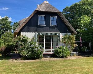 Vorderansicht des Ferienhauses Akkerduin in Ballum, Ameland, mit Reetdach und blhendem Garten auf den Watteninseln.
