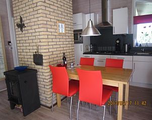 Moderne eetruimte in De Klipper vakantiehuis, Ballum, Ameland met rode stoelen.