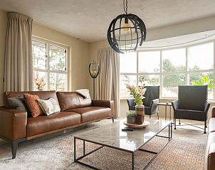 Lichte zithoek in Vakantievilla De Duinen, Buren, Ameland, met grote ramen en comfortabele banken voor een ontspannen verblijf.