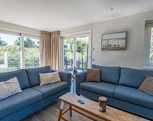 Lichte woonkamer van Kolibrie vakantiehuis in Buren, Ameland met uitzicht op groene omgeving.