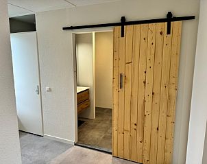 Slaapkamer van Buiten de duinen appartement in Buren, Ameland, met houten schuifdeur en moderne badkamer.