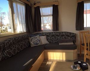 Ruime woonkamer van stacaravan De Hout in Buren, Ameland met uitzicht op de tuin.