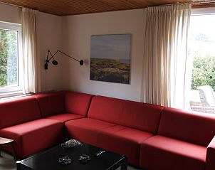 Rode bank in Oase vakantiehuis, Buren, Ameland met uitzicht op natuur.