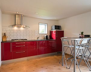 Stijlvolle keuken in appartement Asterix, Buren, Ameland met rode kasten en eetruimte voor een comfortabel verblijf.