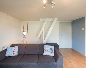 Moderne zithoek in appartement Asterix, Buren, Ameland met comfortabele bank en trap naar bovenverdieping.