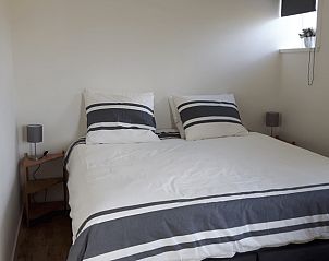 Comfortabele slaapkamer in Vakantiehuisje in Hollum op Ameland met een uitnodigend tweepersoonsbed en rustige sfeer.