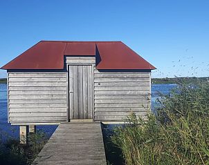 Rustiek houten huisje aan het water bij Vakantiehuisje in Hollum op Ameland, een unieke ervaring op de Waddeneilanden.