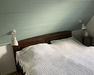 Romantische slaapkamer met houten bed in Beppe van Ameland vakantiehuis, Hollum.