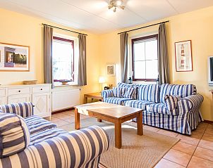 Gezellige woonkamer in Engelsmanduinvilla 8, een bungalow in Hollum, Ameland, met comfortabele banken en veel natuurlijk licht.