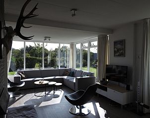 Cozy living room with large windows in Strandloper vacation home, Hollum, Ameland.