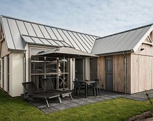 Exterior of VUURTORENLODGE 4, a vacation home in Hollum, Ameland with modern veranda and deck chairs.