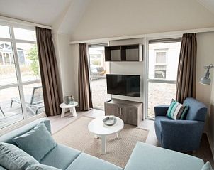 Bright living room in VUURTORENLODGE 4, vacation home in Hollum, Ameland with large windows and modern furnishings.