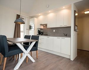 Fully equipped kitchen in VUURTORENLODGE 4, a vacation home in Hollum, Ameland with dining area and modern appliances.