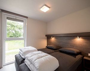 Bedroom in VUURTORENLODGE 4, Hollum, Ameland with double bed and view of green surroundings.