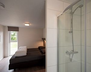 Moderne badkamer en slaapkamer in VUURTORENLODGE 6, vakantiehuis in Hollum, Ameland met ruime douche en comfortabel bed.