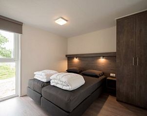 Sfeervolle slaapkamer in AMELANDLODGE 4, vakantiehuis in Hollum, Ameland, met luxe bedden en uitzicht op de groene omgeving.