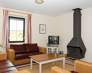 Gemtliches Wohnzimmer der ENGELSMANDUINVILLA 6 in Hollum, Ameland, mit bequemer Sitzecke und Kamin, ideal zum Entspannen.