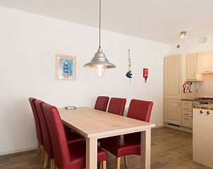 Essbereich der Weidevilla A 6 auf Ameland: stilvoll eingerichteter Raum mit Holztisch und roten Sthlen.