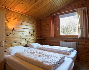 Slaapkamer in FINSE BUNGALOW 4, Hollum, Ameland, met knus houten interieur en uitzicht op de natuur.