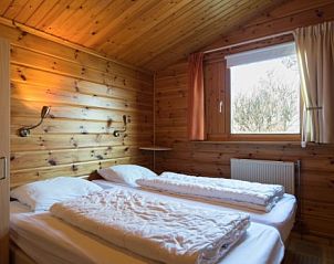 Slaapkamer in FINSE BUNGALOW 6, Hollum, Ameland, met houten wanden en uitzicht op de natuur van de Waddeneilanden.