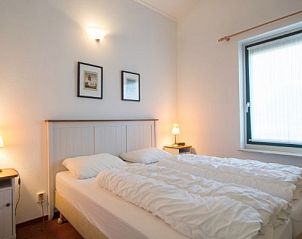 Sfeervolle slaapkamer in FINSE BUNGALOW 6, Hollum, Ameland. Rustgevende inrichting en comfortabele bedden voor een ontspannen verblijf.