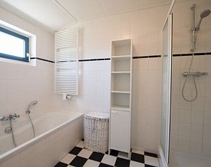 Moderne badkamer in FINSE BUNGALOW 6, Hollum, Ameland. Voorzien van bad en douche, ideaal voor verfrissende momenten op de Waddeneilanden.