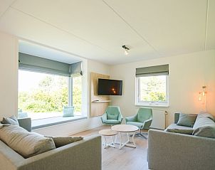Gezellige woonkamer in Duinbungalow Luxe 10, Hollum, Ameland met comfortabele zitplaatsen en uitzicht op de groene omgeving.