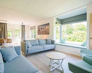 Stijlvolle woonkamer in Duinbungalow Luxe 10, Hollum, Ameland met ruime zithoek en uitzicht op groene omgeving.