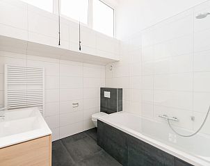 Moderne badkamer in Duinbungalow Luxe 10 in Hollum, Ameland, Waddeneilanden met ligbad en witte tegels.