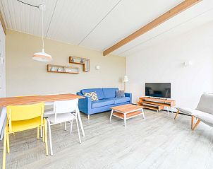 Eetgedeelte van de vrijstaande woning in Hollum, Ameland met kleurrijke stoelen en een grote kaart aan de muur.