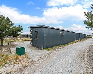 Luchtfoto van vakantiehuizen in Hollum, Ameland met vuurtoren op de achtergrond.