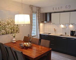 Eetruimte met houten tafel en moderne keuken in Appartement Amelander Kaap 2, Hollum, Ameland, ideaal voor gezellige maaltijden.