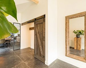 Interieur met houten schuifdeur en spiegel in bungalow Wagenschuur, Hollum, Ameland, Waddeneilanden.