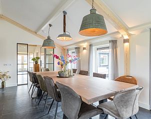 Lichte eetruimte in vakantiehuis Wagenschuur, Hollum, Ameland met grote ramen en moderne verlichting.