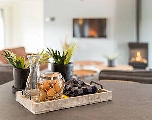 Gezellige details op het aanrecht in de keuken van Wagenschuur bungalow, Hollum, Ameland met open haard op achtergrond.