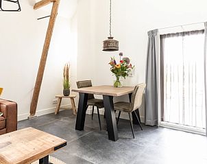 Eethoek in Dorsvloer appartement in Hollum, Ameland. Knusse ruimte met houten tafel en stijlvolle stoelen naast een groot raam.