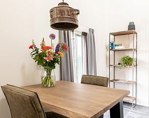 Detail van de eethoek in Dorsvloer appartement, Hollum, Ameland. Bloemen op tafel en een industrieel hanglamp voor sfeervol dineren.