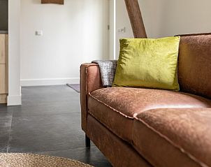 Detail van de bank in Dorsvloer appartement, Hollum, Ameland. Leren bank met kleurrijke kussens voor extra comfort.