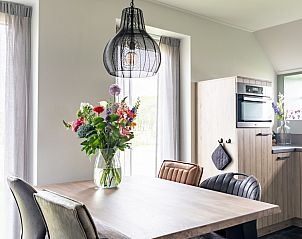 Gezellige eetruimte in De Deel, appartement in Hollum, Ameland met moderne inrichting en bloemen op tafel.